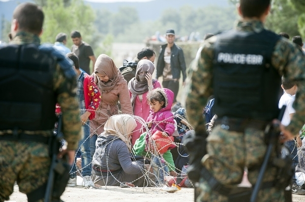 Migrants wait to cross the Macedonian-Greek border near the town of Gevgelija on August 21, 2015. At least five migrants were slightly hurt August 21 when Macedonian police threw noise grenades to drive back refugees from the country's border with Greece, an AFP photographer at the scene said. More than 3,000 mostly Syrian refugees are stuck in no-man's land near the Greek village of Eidomeni after Macedonia August 20 declared a state of emergency and sent troops to help stem the flow of migrants attempting to cross the Balkan country to reach northern Europe. AFP PHOTO / ROBERT ATANASOVSKI