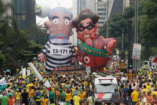 Des manifestants montrent une énorme poupée gonflable à l'effigie de l'ancien président du Brésil Luiz Inacio Lula da Silva en tenue de prisonnier et l'actuelle présidente Dilma Rousseff habillée en voleuse, avec une écharpe où on peut lire 