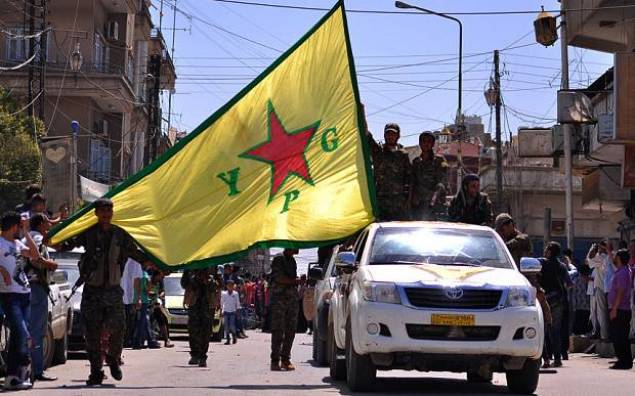 Des combattants kurdes des Unités de protection du peuple (YPG) agitent le drapeau de leur mouvement lors d’un défilé à Qamichli en février 2015. AFP