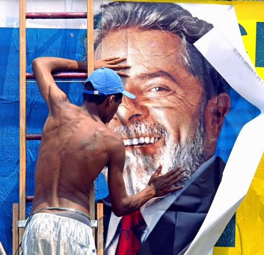 Un travailleur colle une affiche de campagne pour le candidat brésilien à la présidence Luiz Inacio Lula da Silva, du Parti des Travailleurs(PT), le 24 octobre 2002, à Sao Paulo, au Brésil. Photo: Marucio Lima/AFP/Getty Images